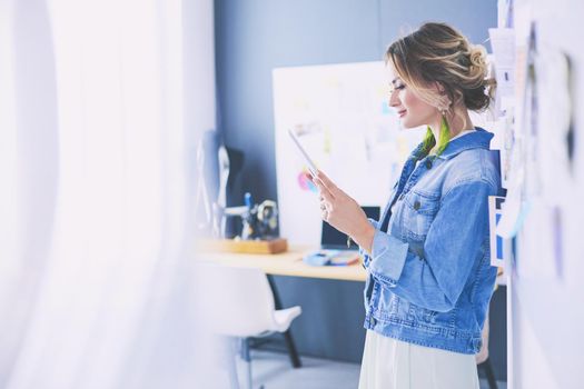 Fashion designer woman working on her designs with ipad in the studio.