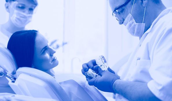 Portrait of a dentist who treats teeth of young woman patient.