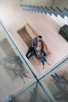 Young couple sitting on a sofa in the luxury living room, using a tablet computer top view