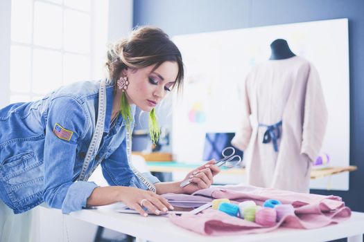 Fashion designer woman working with ipad on her designs in the studio.