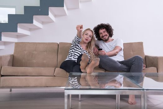 Young couple on the sofa watching television together in their luxury home