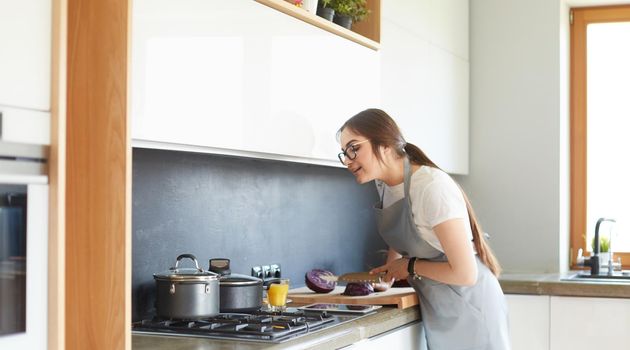 Young woman using a tablet computer to cook in her kitchen.