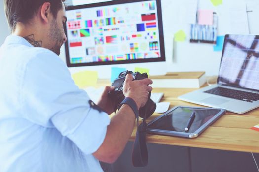 Portrait of young designer sitting at graphic studio in front of laptop and computer while working online