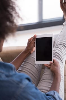 Young african american woman at home relaxing in her luxury lliving room reading a digital tablet PC surf internet and work