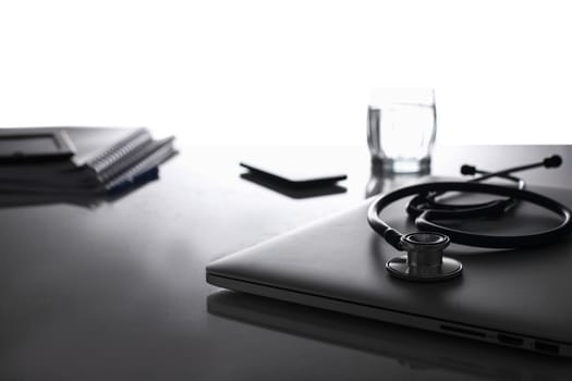 Medical stethoscope laptop and documents on desk.