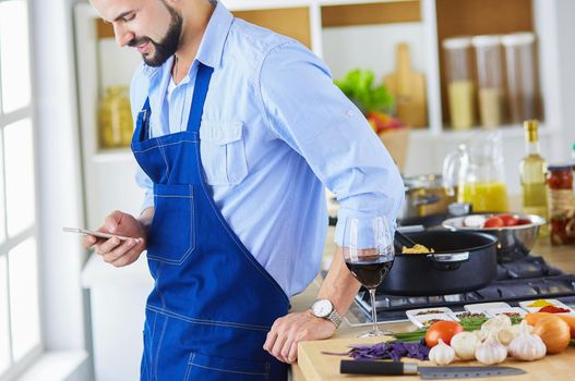 Man holding paper bag full of groceries on the kitchen background. Shopping and healthy food concept.