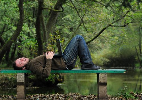 one young businessman working on laptop outdoor with green nature in background