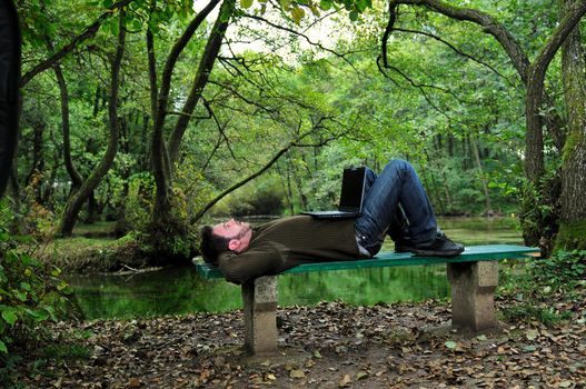 one young businessman working on laptop outdoor with green nature in background