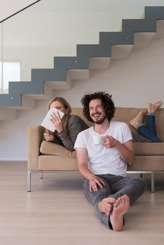 Young couple relaxing at luxurious home with tablet computers reading in the living room on the sofa couch.