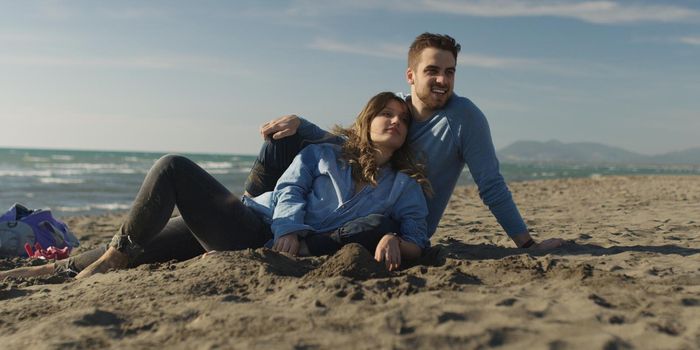 Young Couple having fun and Playing With A Kite On The Beach at autumn day