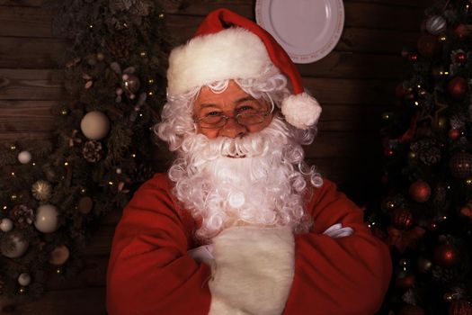 Traditional Santa Claus standing by the Christmas tree in a room