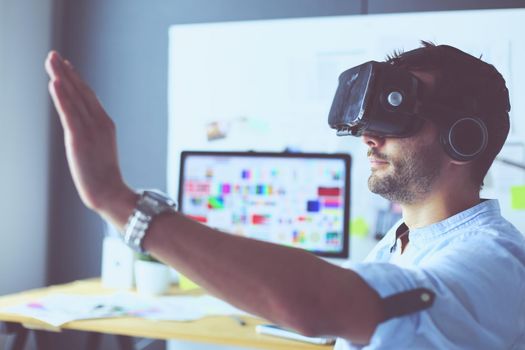 Young male software programmer testing a new app with 3d virtual reality glasses in office