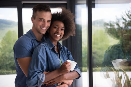 romantic happy young multiethnic couple enjoying morning coffee by the window in their luxury home