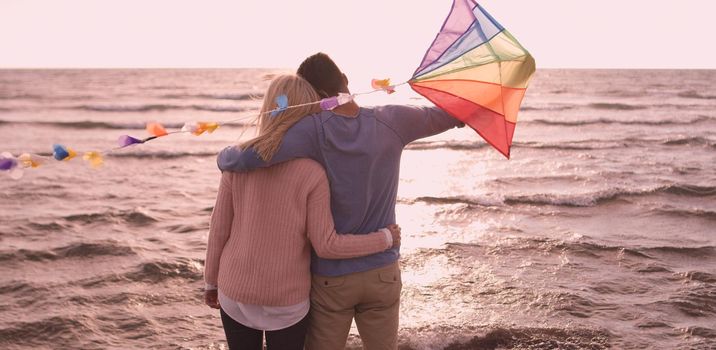 Loving Couple Flying A Kite at Beach and having fun on autumn day