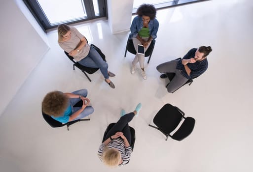 Multiethnic startup business team on meeting in modern bright office interior brainstorming, working on laptop and tablet computer top view