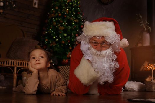 Santa Claus and child laying on floor at home. Christmas gift. Family holiday concept