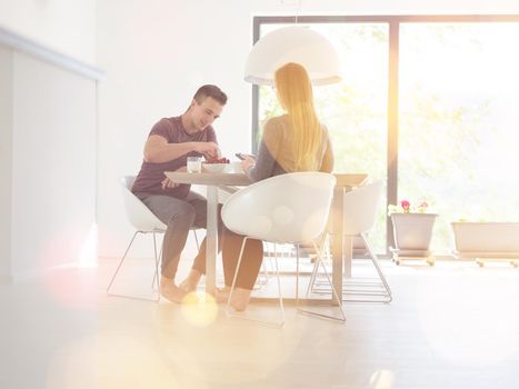 young beautiful handsome couple enjoying morning coffee and strawberries in their luxurious home villa