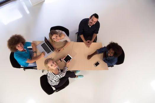 Multiethnic startup business team on meeting in modern bright office interior brainstorming, working on laptop and tablet computer top view