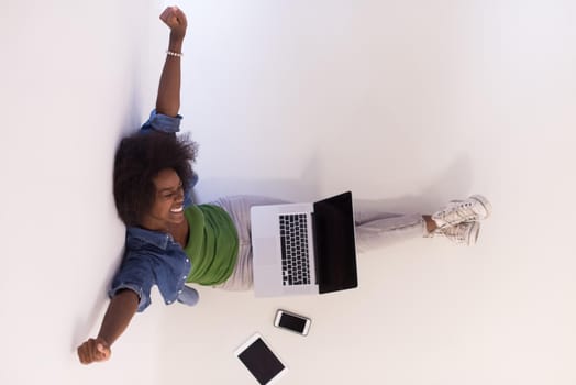 Portrait of happy young african american woman sitting on floor with laptop top view