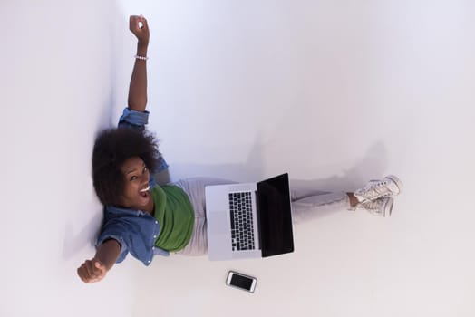 Portrait of happy young african american woman sitting on floor with laptop top view