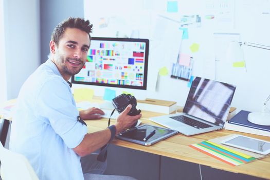 Portrait of young designer sitting at graphic studio in front of laptop and computer while working online