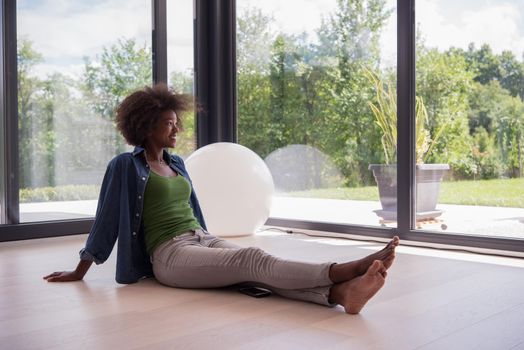 Beautiful african american young woman in casual fashion clothes sitting near window