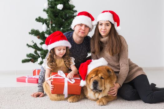 Pet, holidays and festive concept - Family with dog are lying on floor near christmas tree