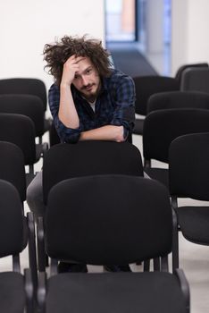 A student sits alone in a empty seats in a classroom