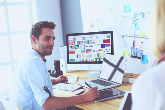 Portrait of young designer sitting at graphic studio in front of laptop and computer while working online