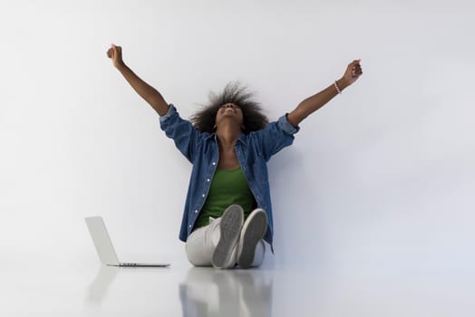 Portrait of happy young african american woman sitting on floor with laptop