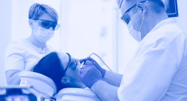 Portrait of a dentist who treats teeth of young woman patient.