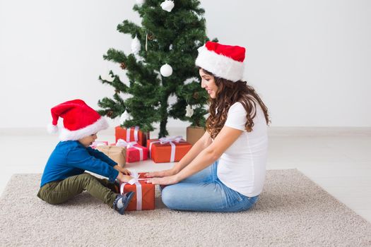 Christmas, single parent and holidays concept - Cute little boy holding christmas present for his mother at the home
