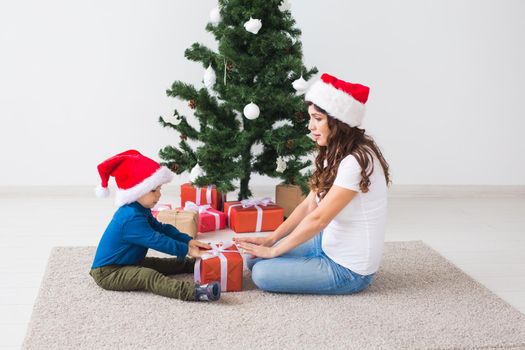 Christmas, single parent and holidays concept - Cute little boy holding christmas present for his mother at the home