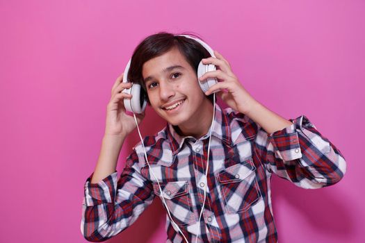 Arabic Teenage Boy Wearing Headphones And Listening To Music pink background