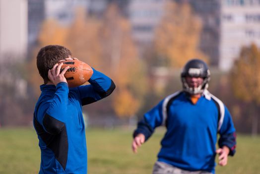 Team coach throwing the ball into the group of young american football players in action during the training at the field