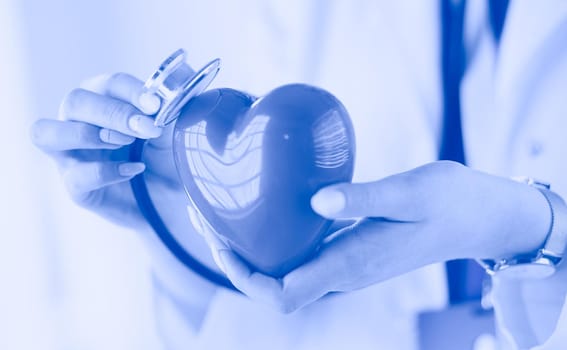 A doctor with stethoscope examining red heart, isolated on white background.