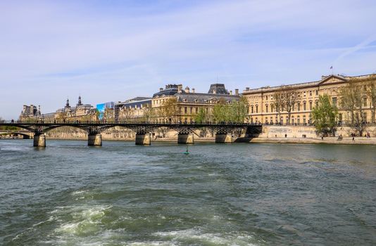 Pedestrian bridge (Pont des Arts) over Seine river and historic buildings of Paris France