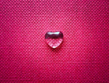 A transparent heart on backdrop of pink textile texture. Perfect Valentine's Day greeting card background.