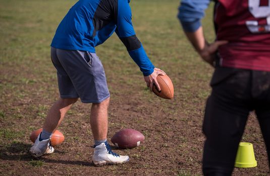 Team coach throwing the ball into the group of young american football players in action during the training at the field