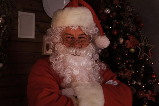 Traditional Santa Claus standing by the Christmas tree in a room