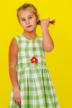 A sweet girl straightens her hair. The concept of fashion and style.On a yellow background.