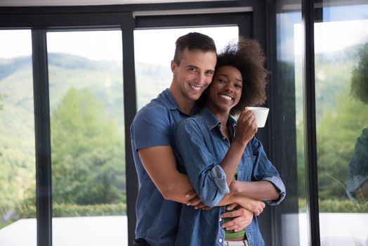 romantic happy young multiethnic couple enjoying morning coffee by the window in their luxury home