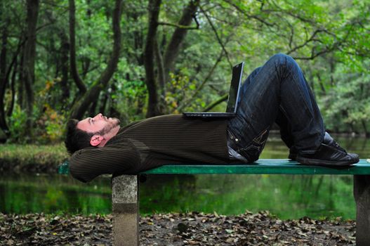 one young businessman working on laptop outdoor with green nature in background