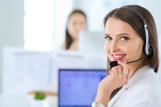 Smiling businesswoman or helpline operator with headset and computer at office.