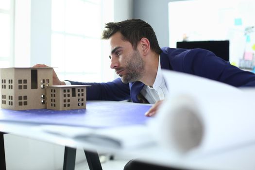 Businessman holding house miniature on hand standing in office
