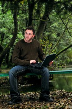 one young businessman working on laptop outdoor with green nature in background