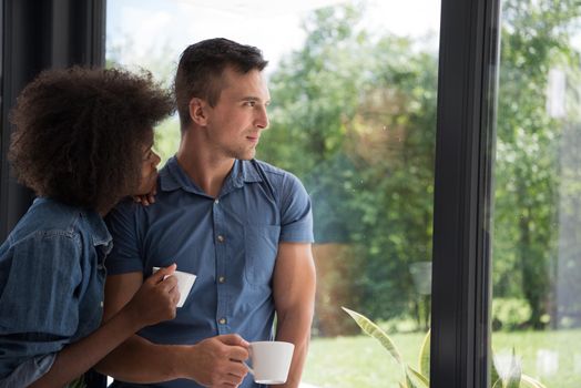 romantic happy young multiethnic couple enjoying morning coffee by the window in their luxury home