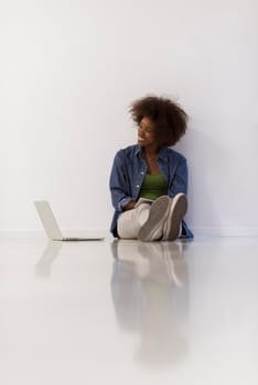 Portrait of happy young african american woman sitting on floor with laptop