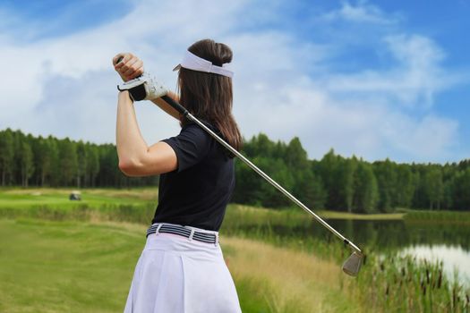 Woman golfer hits an fairway shot towards the club house