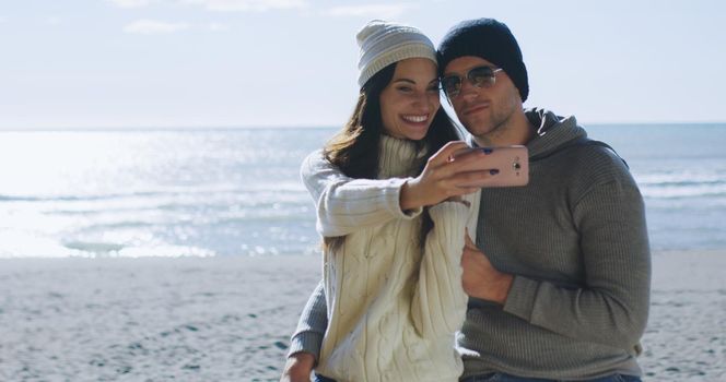 Very Happy Couple In Love Taking Selfie On The Beach in autmun day